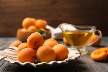 Plate with fresh apricots on wooden table