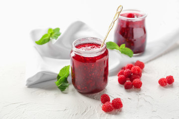 Jar with tasty raspberry jam on light table