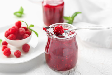 Jar with tasty raspberry jam on light table