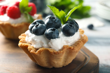 Tasty tartlet with blueberries on wooden board, closeup