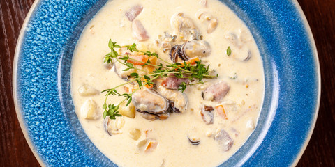 The concept of Italian cuisine. Creamy soup with seafood, mussels, potatoes, carrots, thyme. serve in a blue plate.