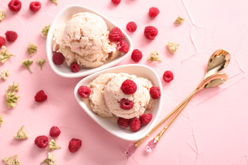 Bowls with tasty ice-cream and raspberries on color background