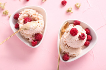 Bowls with tasty ice-cream and raspberries on color background