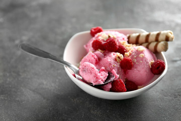 Bowl with tasty raspberry ice-cream on grey table