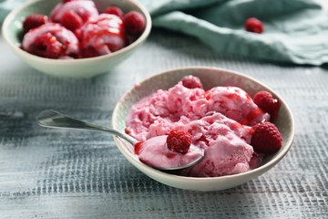 Bowls with tasty raspberry ice-cream on wooden table