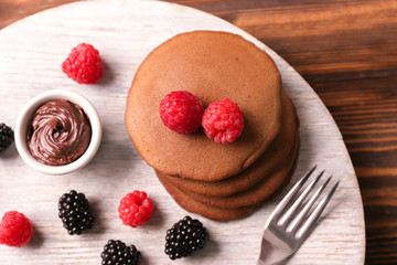Stand with tasty chocolate pancakes on wooden table