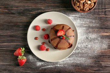 Plate with tasty chocolate pancakes on wooden table
