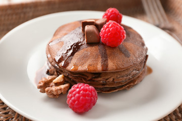 Plate with tasty chocolate pancakes and berries on table, closeup