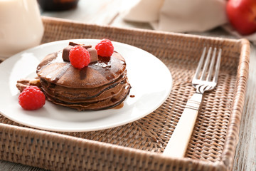 Tray with tasty chocolate pancakes and berries on wooden table