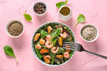 Bowl of delicious vegetable salad with seafood on table