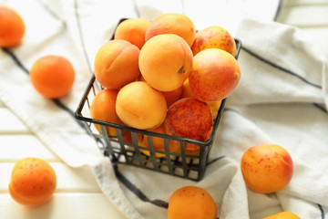 Container with fresh apricots on wooden table