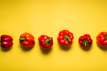 Fresh red bell peppers on bright yellow background, top view