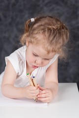 Little girl draws with pencils, portrait on background of school board