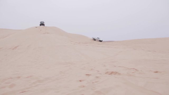 Wide shot of a pickup truck and a landcruisre going downhill. Side shot.