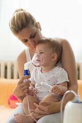 Baby taking respiratory inhalation therapy. Mother holding the mask of a nebuliser