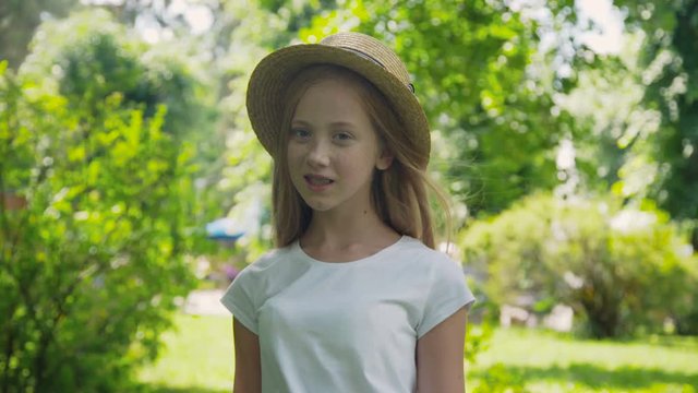 Portrait of pretty girl poses at camera with colourful balloons in sunny park