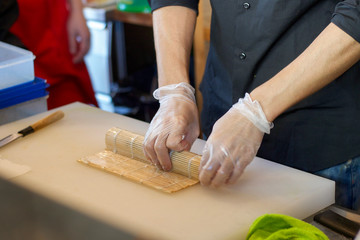 japanese chef preparing sushi roll with bamboo mat