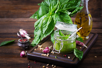 Homemade pesto sauce fresh basil, pine nuts and garlic on wooden background. Italian food.