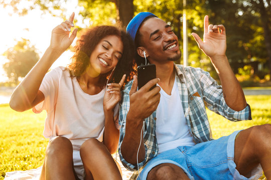 Portrait of a joyful young african couple in earphones