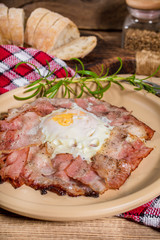 Plate of breakfast with fried eggs, bacon and bread.