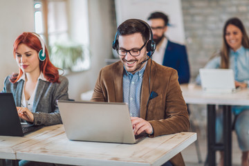 Portrait of happy smiling customer support phone operator at workplace.