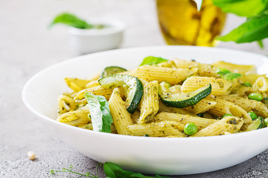 Penne pasta with  pesto sauce, zucchini, green peas and basil. Italian food.