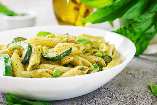 Penne pasta with  pesto sauce, zucchini, green peas and basil. Italian food.