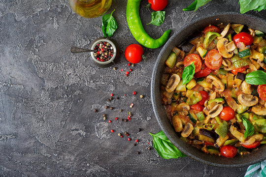 Hot spicy stew eggplant, sweet pepper, tomato, zucchini and mushrooms. Flat lay. Top view