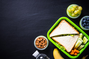 Fototapeta na wymiar Lunch box with sandwich, vegetables, banana, water, nuts and ber