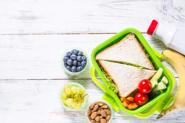 Gordijnen Lunch box with sandwich, vegetables, yogurt, nuts and berries. © nadianb