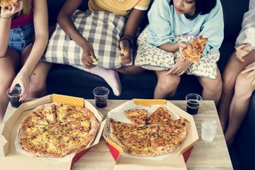 Diverse women sitting on the couch eating pizza together