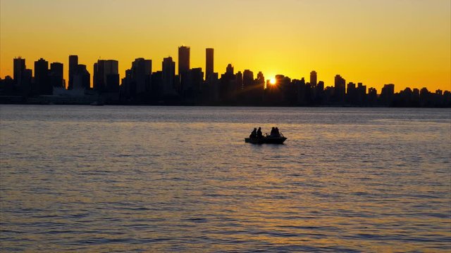 Sun setting behind city skyline as approaching ferry nears dock