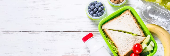 Zelfklevend Fotobehang Lunchbox met sandwich, groenten, yoghurt, noten en bessen. © nadianb