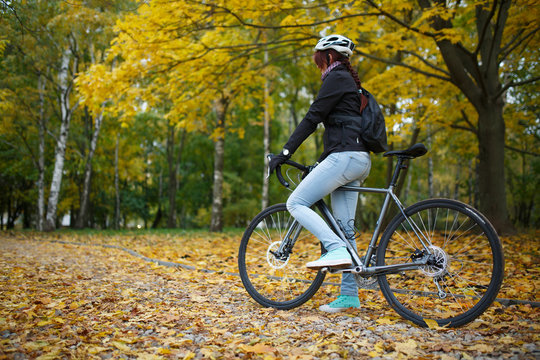 Photo of girl in helmet riding bicycle in autumn forest