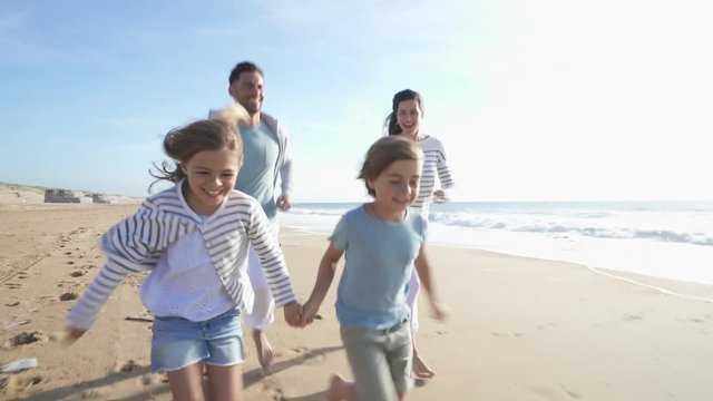 Family walking on sandy beach at sunset