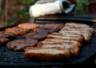 Rows of sausages and hamburgers on a barbecue
