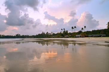 Naklejka premium Wet sands coast with reflection on resort at sunset, Bintan, Indonesia.