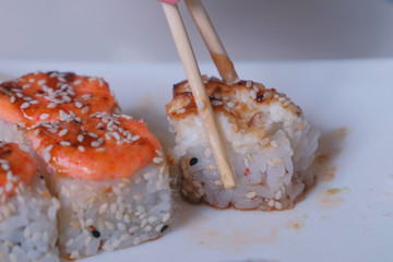 Woman eats rolls with chopsticks. Hand close-up.