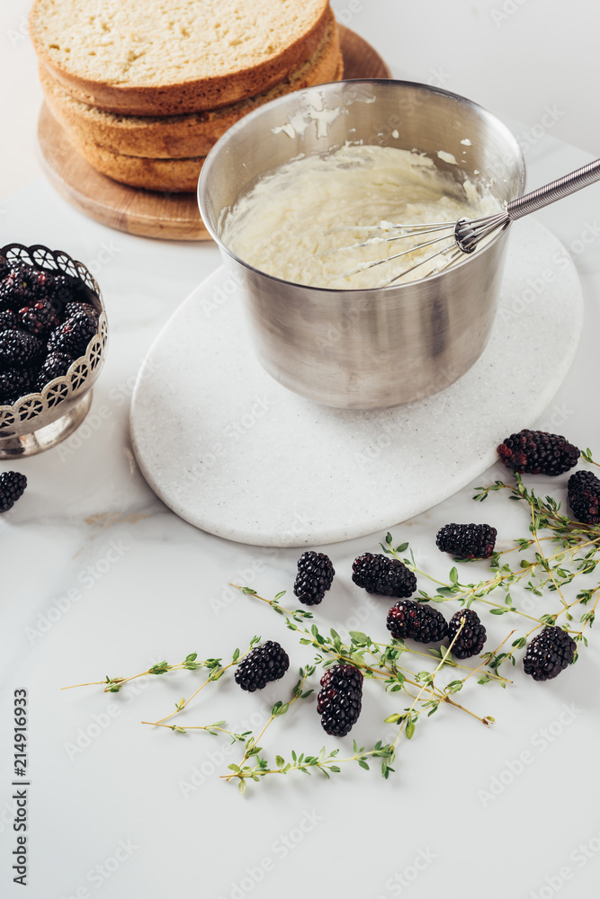 Canvas Prints cropped shot of metal bucket with whisk and cream for cake and blackberries on white table