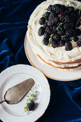 high angle view of freshly baked blackberry cake with plate and cake server o blue cloth