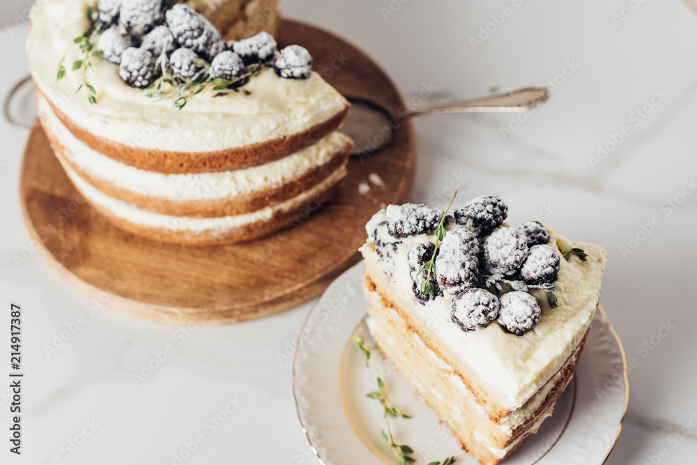 Wall mural close-up shot of tasty sliced blackberry cake on wooden cutting board with cake server and on plate