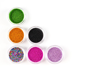 Obraz na płótnie Canvas Sequins for nails of different colors in an assortment in boxes on a white background