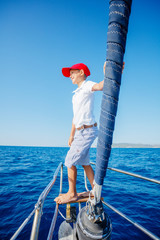 Little boy on board of sailing yacht on summer cruise. Travel adventure, yachting with child on family vacation.