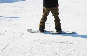 Snowboarding legs on winter mountain top. Snowboarder is riding from snow hill