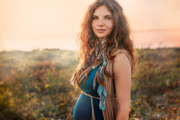 beautiful pregnant woman on a field at sunset