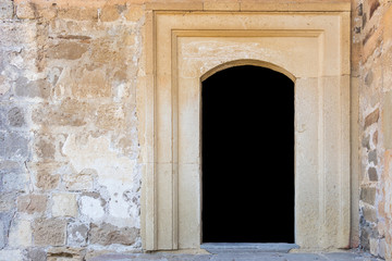 A door in a stone wall is isolated on a black background with copy space