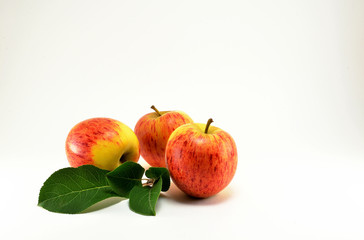 Three ripe red apples and a green twig.