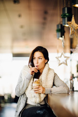 Portrait of a young, attractive woman, sitting alone at a bar, drinking coffee, waiting, enjoying.
