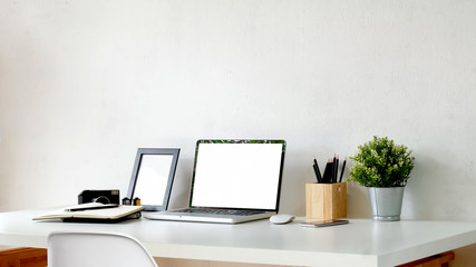 Mockup laptop with mockup poster and office supplies on white wood desk.