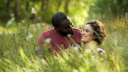 Couple in love spending weekends together sitting in high grass at park, outdoor
